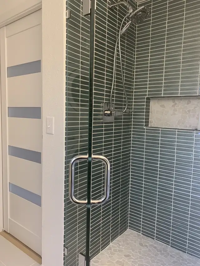 Walk-in shower with green glass stacked tile, recessed niche and frameless glass door