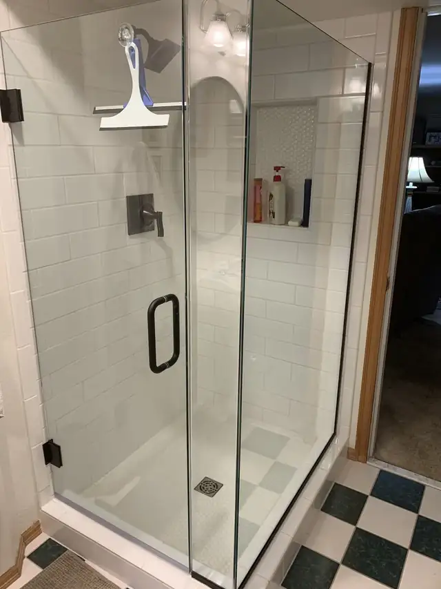 Frameless glass walk-in shower with white tile walls, a recessed niche and a black and white checkered floor
