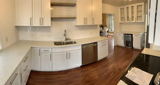 White shaker kitchen with speckled quartz counters, subway tile backsplash, open shelves and dark wood floor